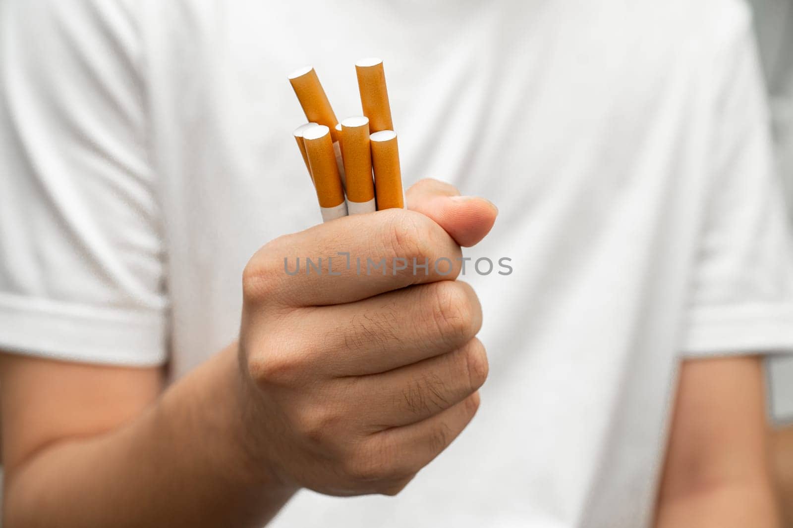 Asian man holding cigarette in hand, no smoking.