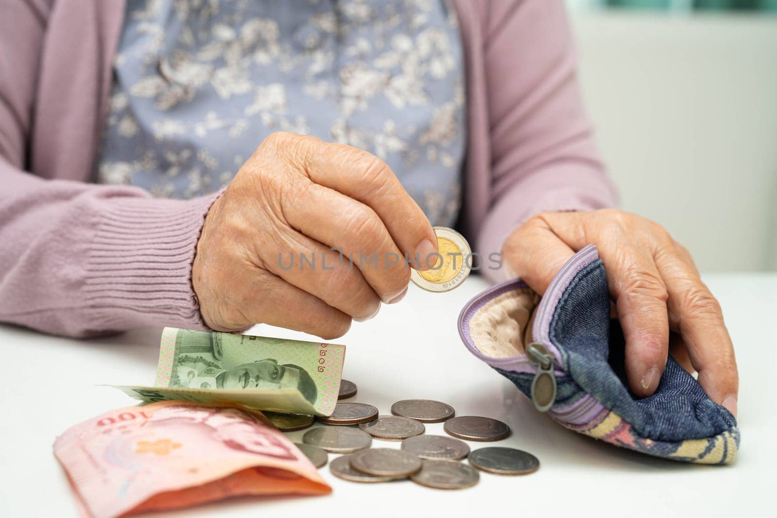 Asian senior or elderly old lady woman holding counting coin money in bag. Poverty, saving problem in retirement.