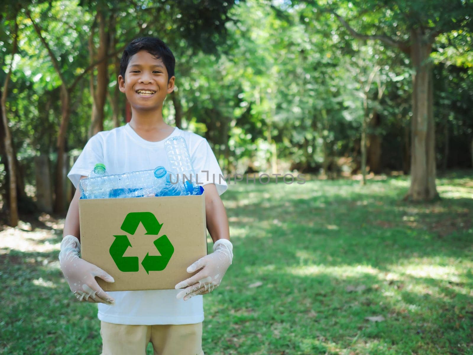 Boy hold cardboard boxes for recycling and holding a recycle bin with plastic bottles in the outdoors, Reduction environmental pollution and recycle concept, Plastic-free, Junk food plastic packaging.