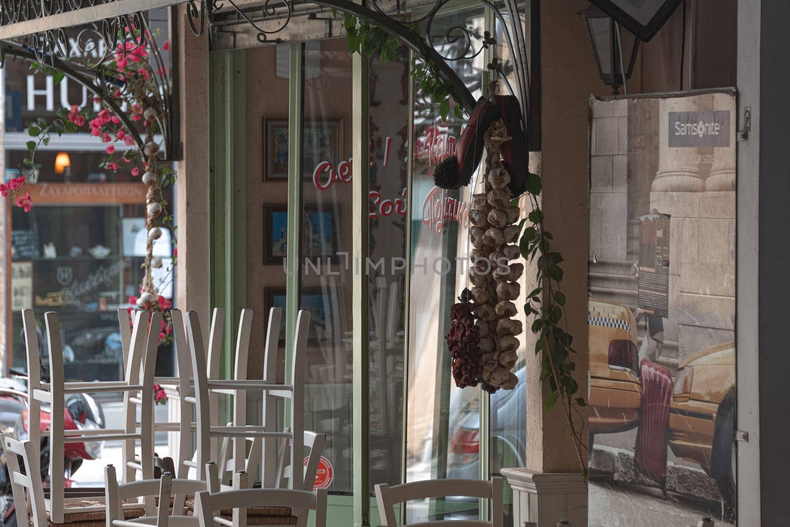 Nicosia, Cyprus - May 22, 2020: White chairs stacked on tables of a traditional cypriot restaurant decorated with hanging garlic and peppers