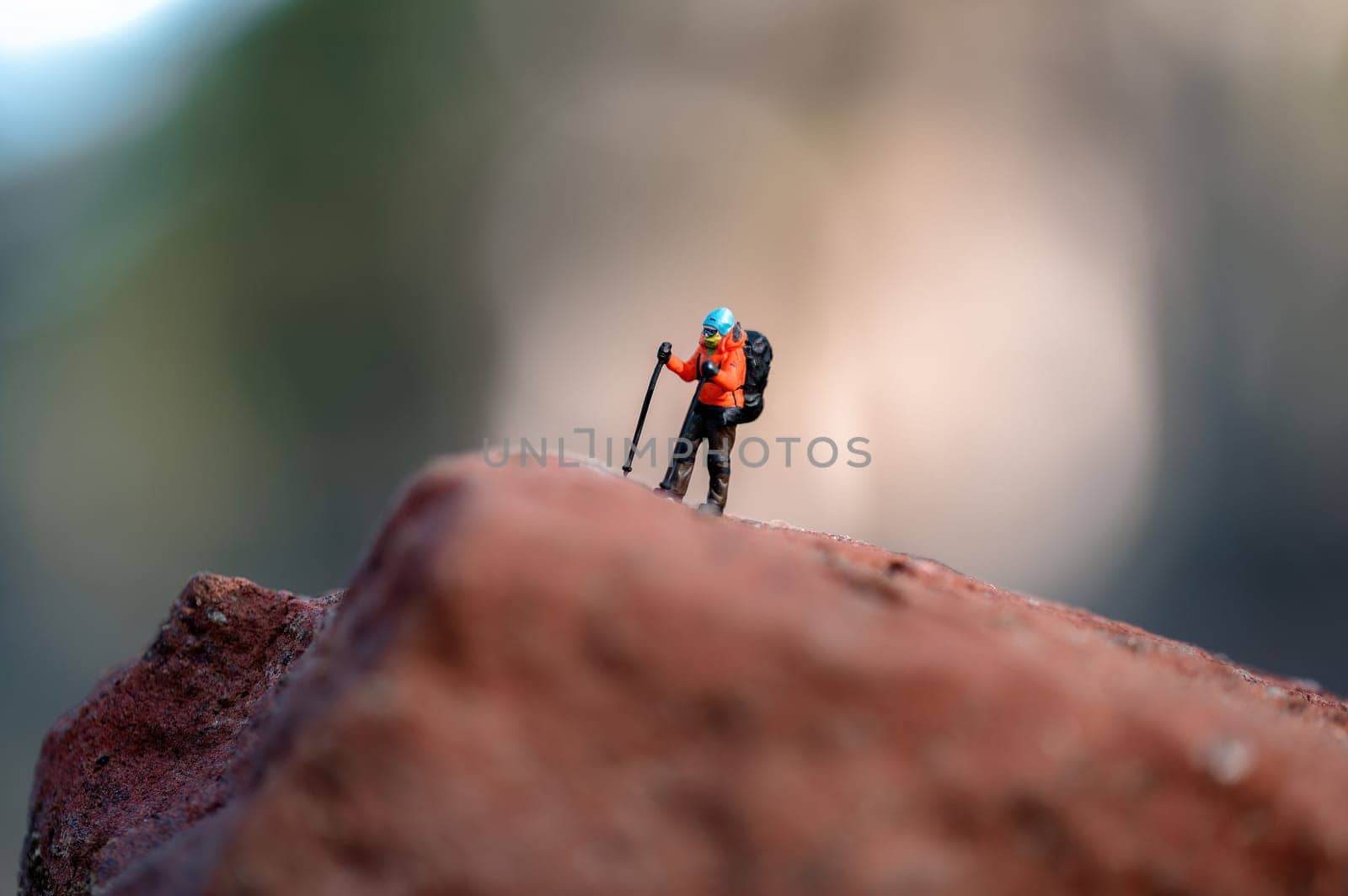Miniature hiker figurine standing on a rock, enjoying the view from the top