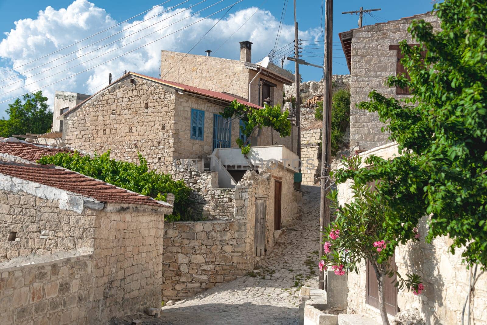 Traditional stone houses with tiled roofs lining a narrow cobblestone street in Vouni village. Limassol District, Cyprus