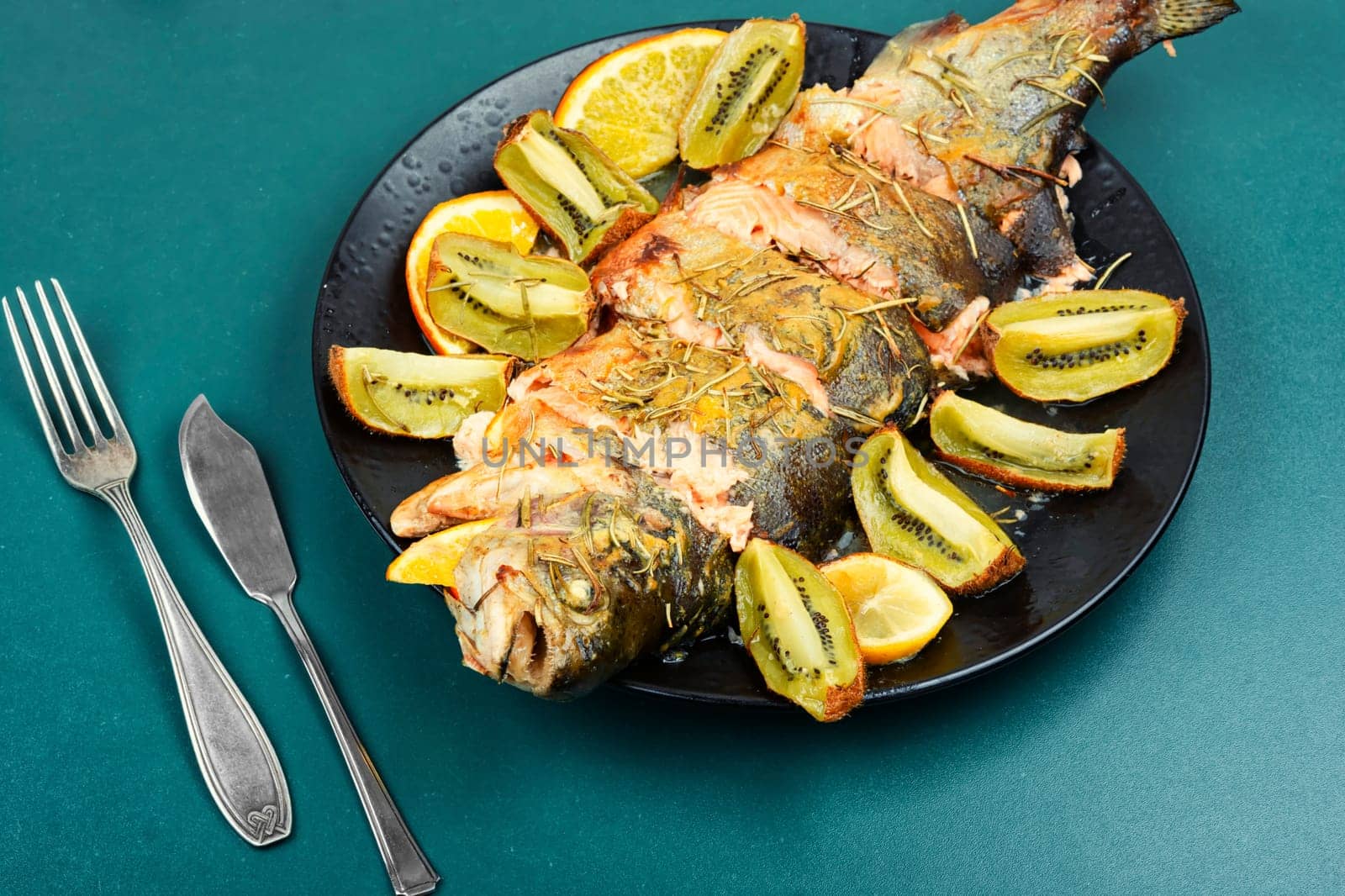 Roasted trout on a plate, baked trout with fruit. Restaurant menu, dieting.