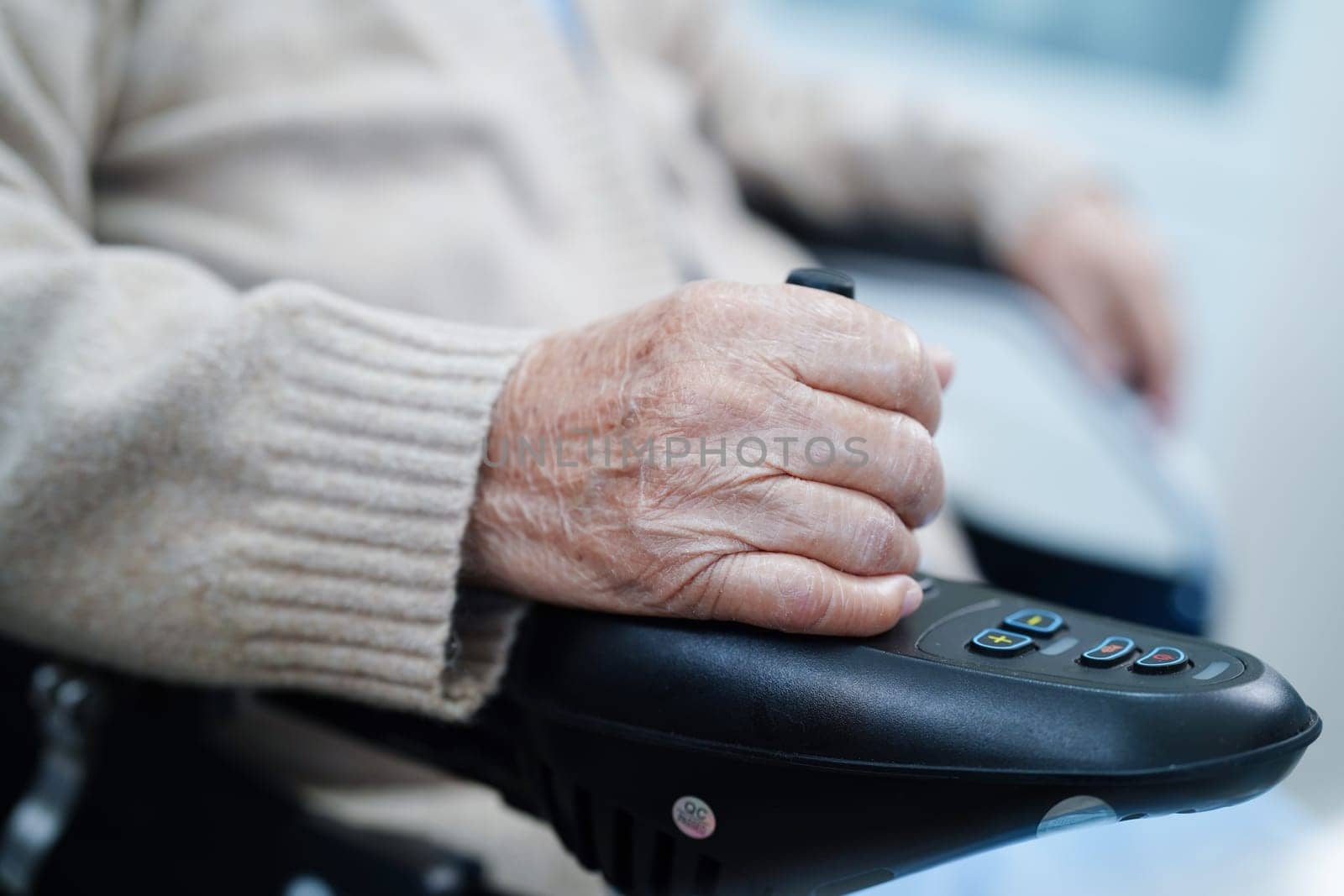 Asian elderly disability woman patient use joystick electric wheelchair in hospital.