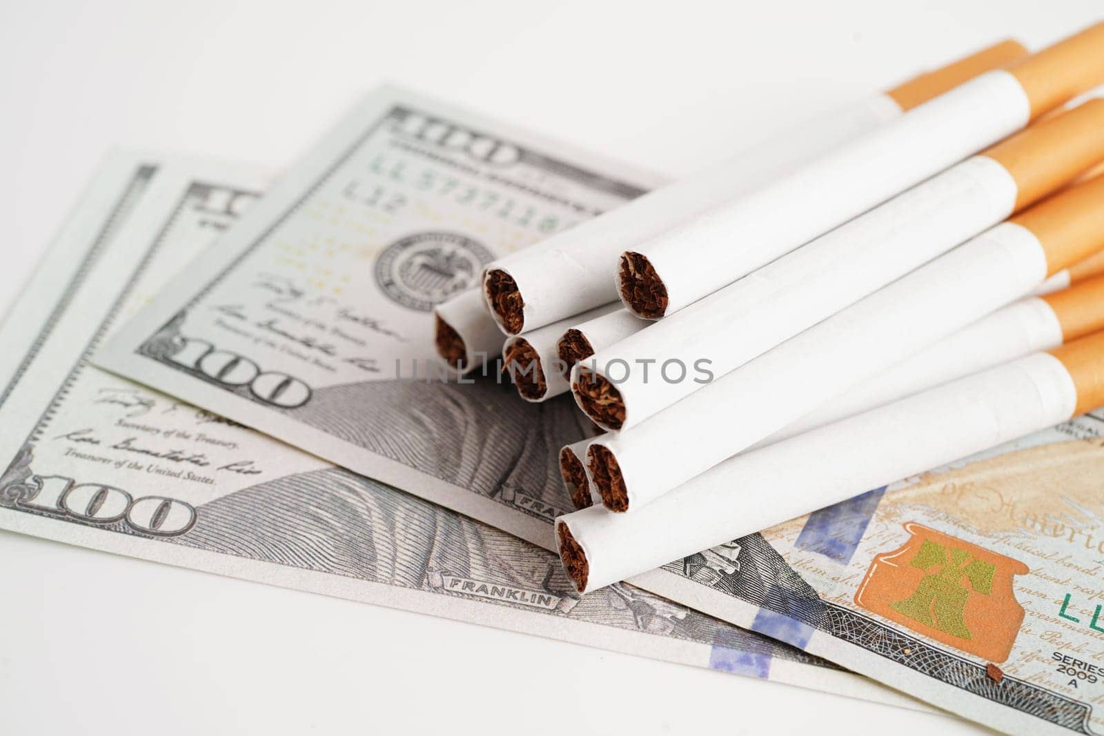 Cigarette on US dollar banknotes, cost, trading, marketing and production, No smoking concept.