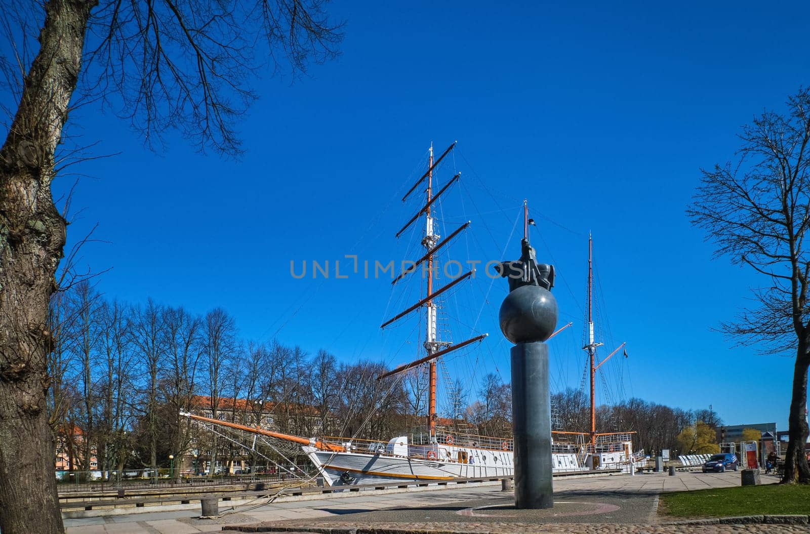 Sailing boat or barquentine anchored in old town of Klaipeda, Lithuania, and monument to millenium of Lithuanian history.