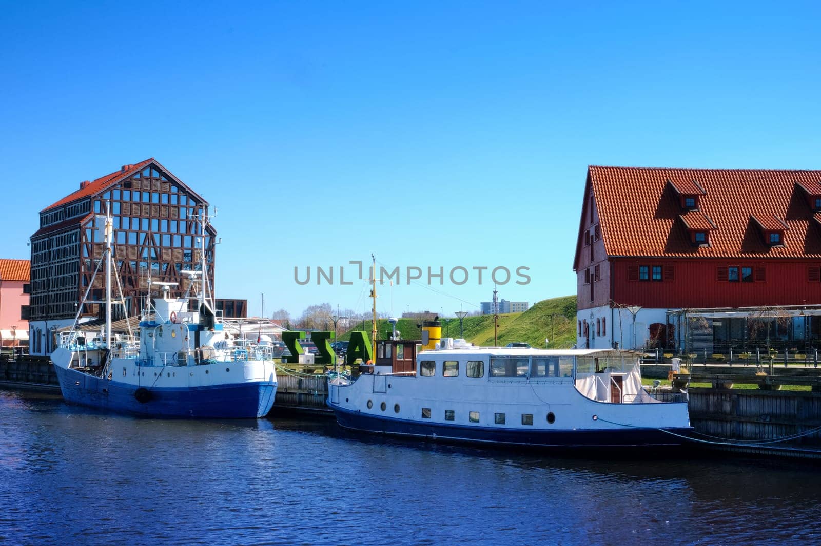 Jetty for boats and yachts in Klaipeda, Lithuania, on sunny day. Beautiful view of vessels and fachwerk and red-brick houses.