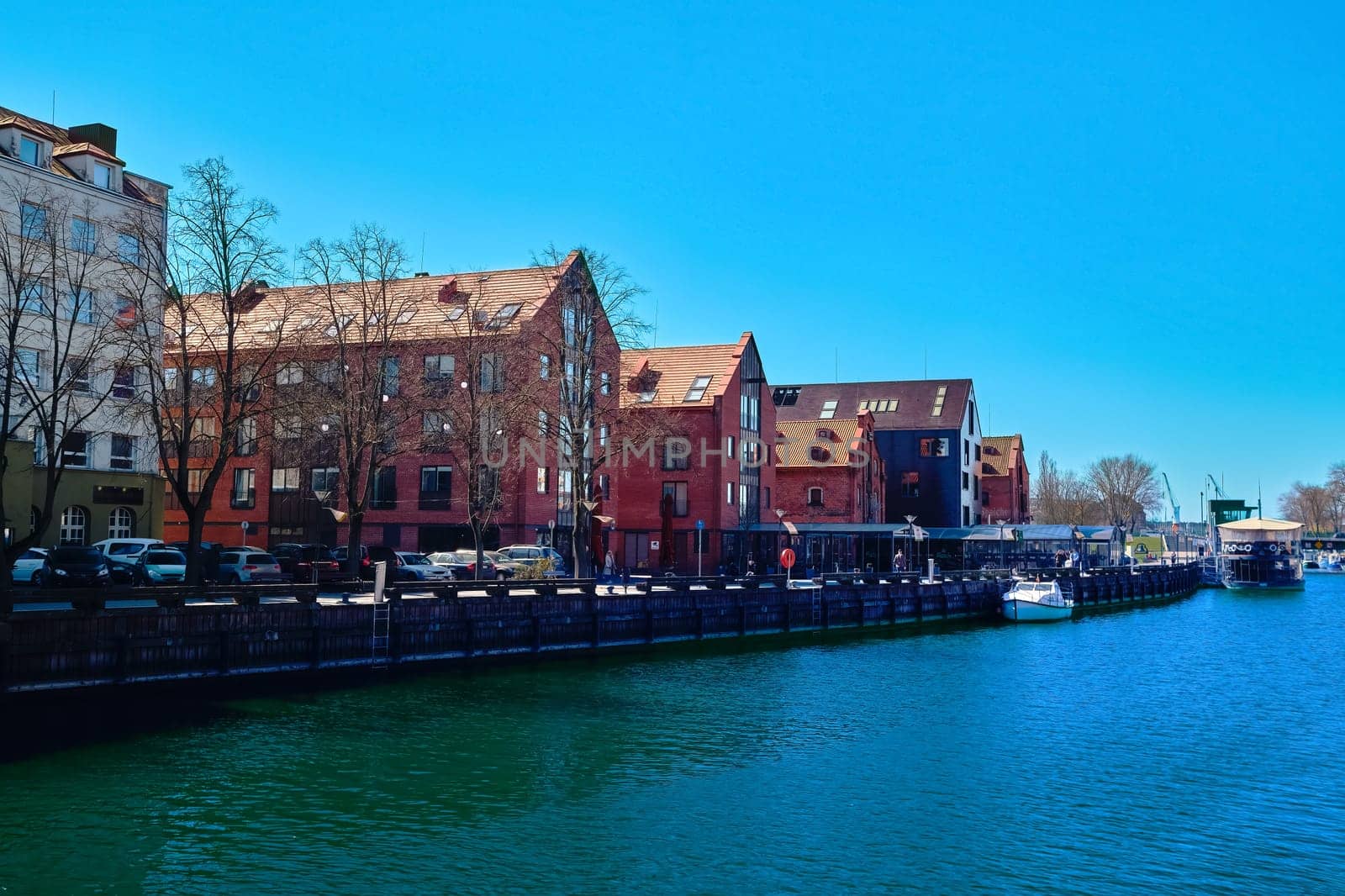Jetty for boats and yachts in Klaipeda, Lithuania, on sunny day. Beautiful view of vessels and fachtwerk and red-brick houses.