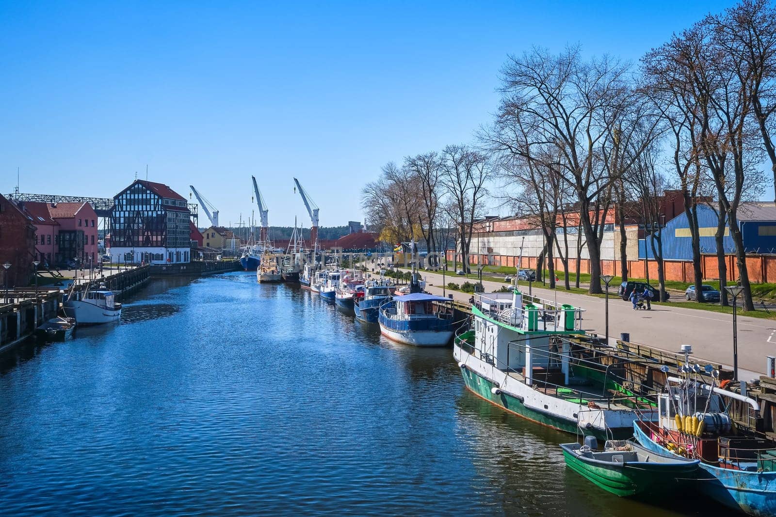 Jetty for boats and yachts in Klaipeda, Lithuania, on sunny day. Beautiful view of vessels and fachwerk and red-brick houses.