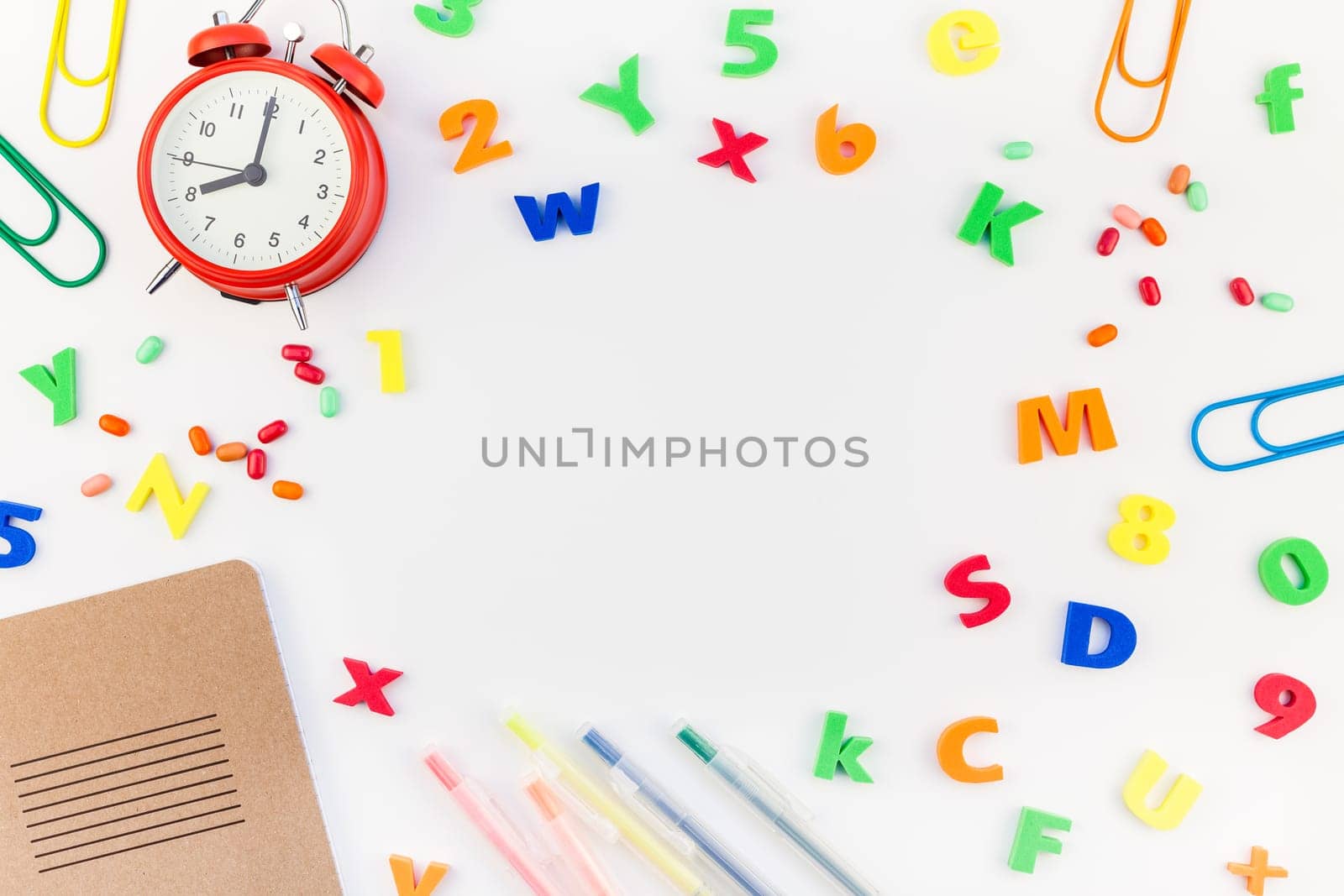 Creative flat lay back to school concept with alarm clock, color school and office supplies on white table background with copy space, frame, template for text or design
