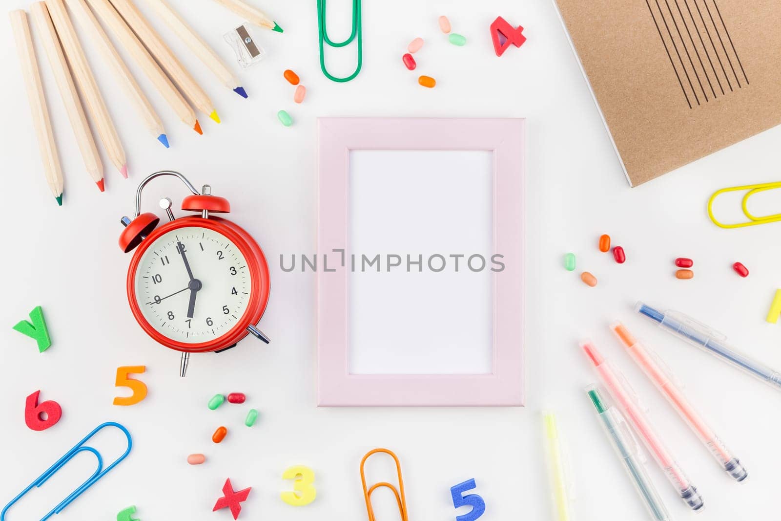 Creative flat lay back to school concept with alarm clock, color school and office supplies on white table background with copy space, frame, template for text or design