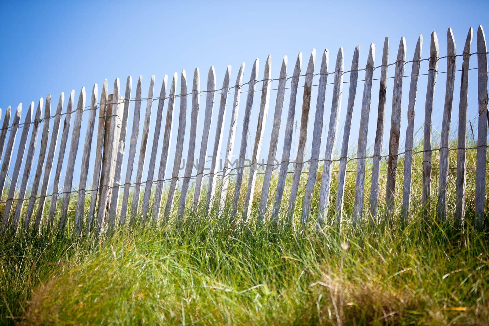 Wooden fence, Green Grass and Blue Sky. Horizontal shot