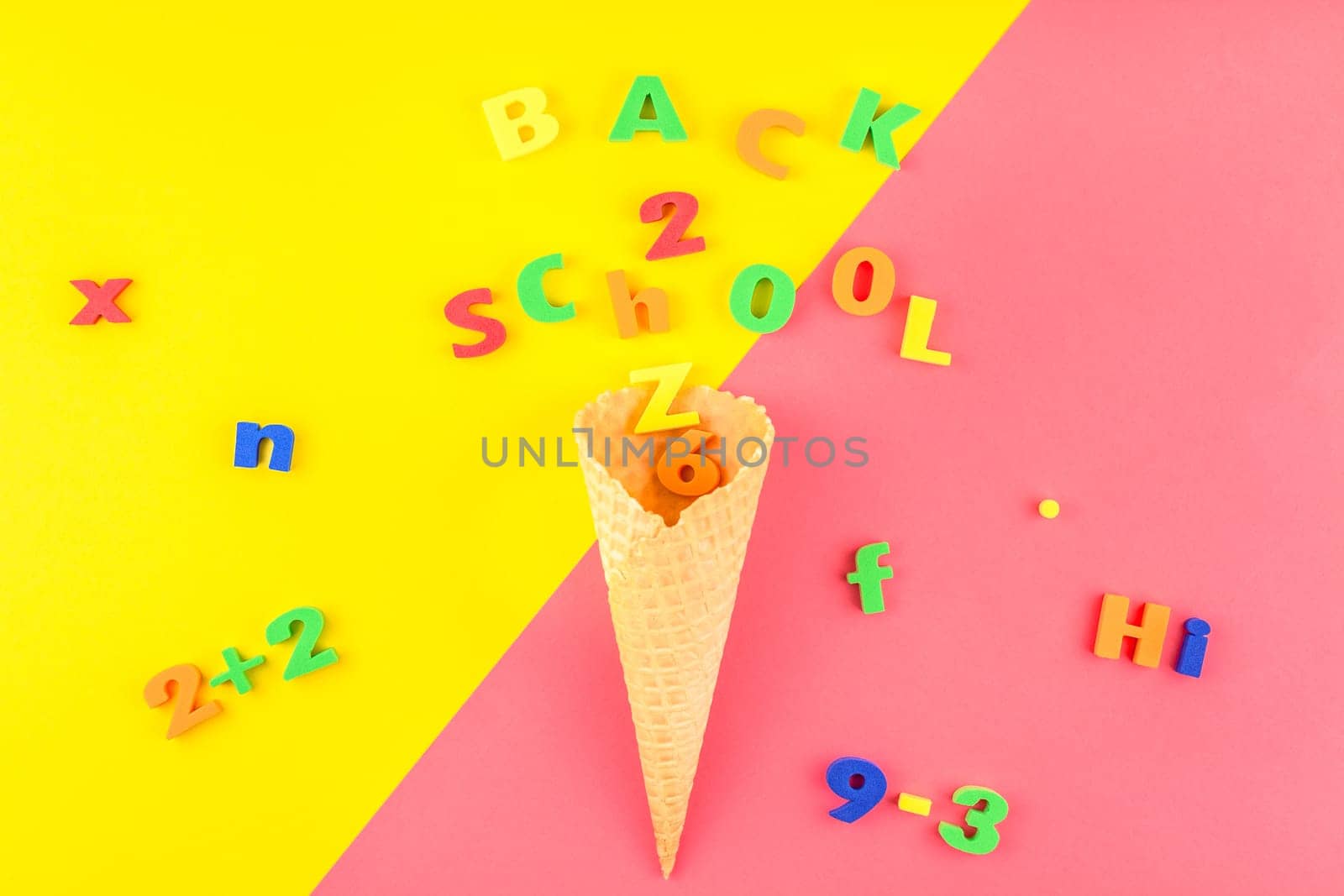 Creative flat lay back to school concept with waffle cone and welcome letters message on bright yellow and pink paper background with copy space, template for text or design