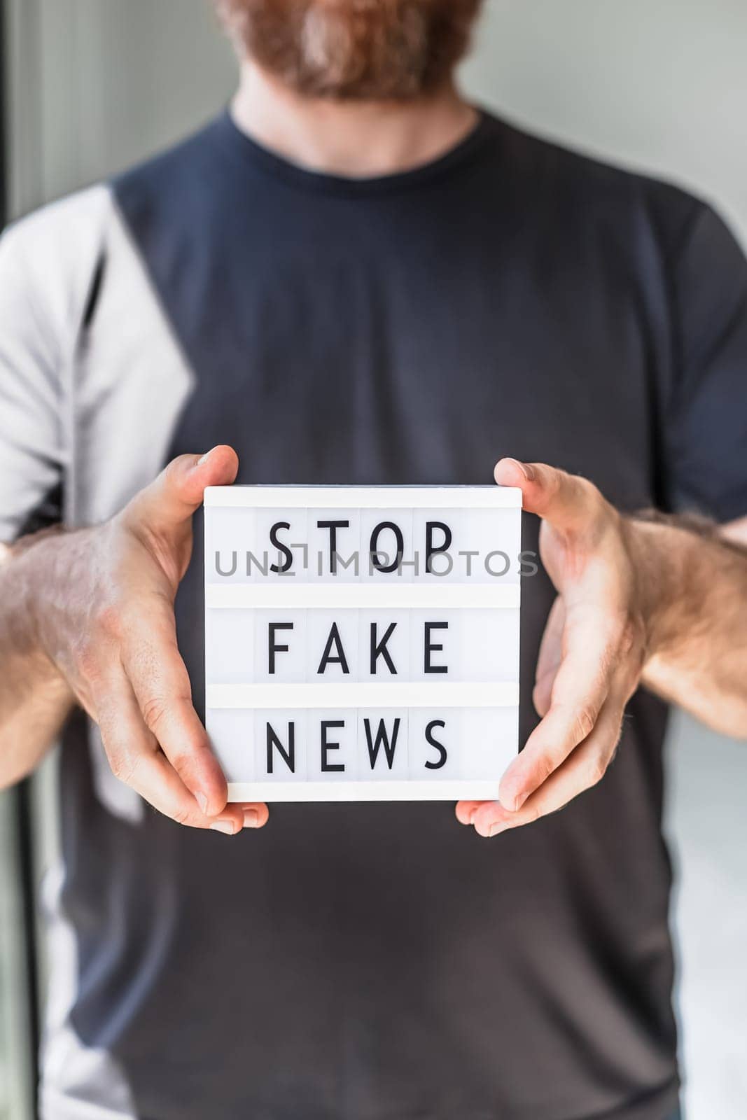 Fake news infodemics during Covid-19 pandemic concept. Man hands holding lightbox with text Stop fake news on foreground. People want to know the truth about coronavirus world spread.