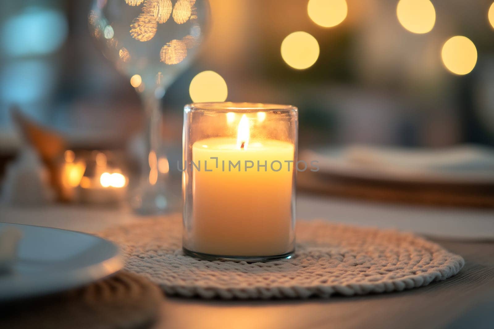 A flickering candle casts a soft glow on a well-set dining table, creating a warm and inviting atmosphere perfect for a cozy dinner.