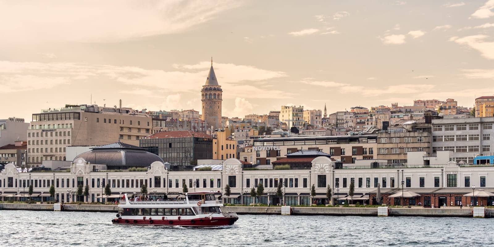 Istanbul, Turkey - September 1, 2022: A ferry navigates the Bosphorus Strait in front of Galataport, a mixed-use development in the Karakoy neighborhood, with the Galata Tower visible in the distance