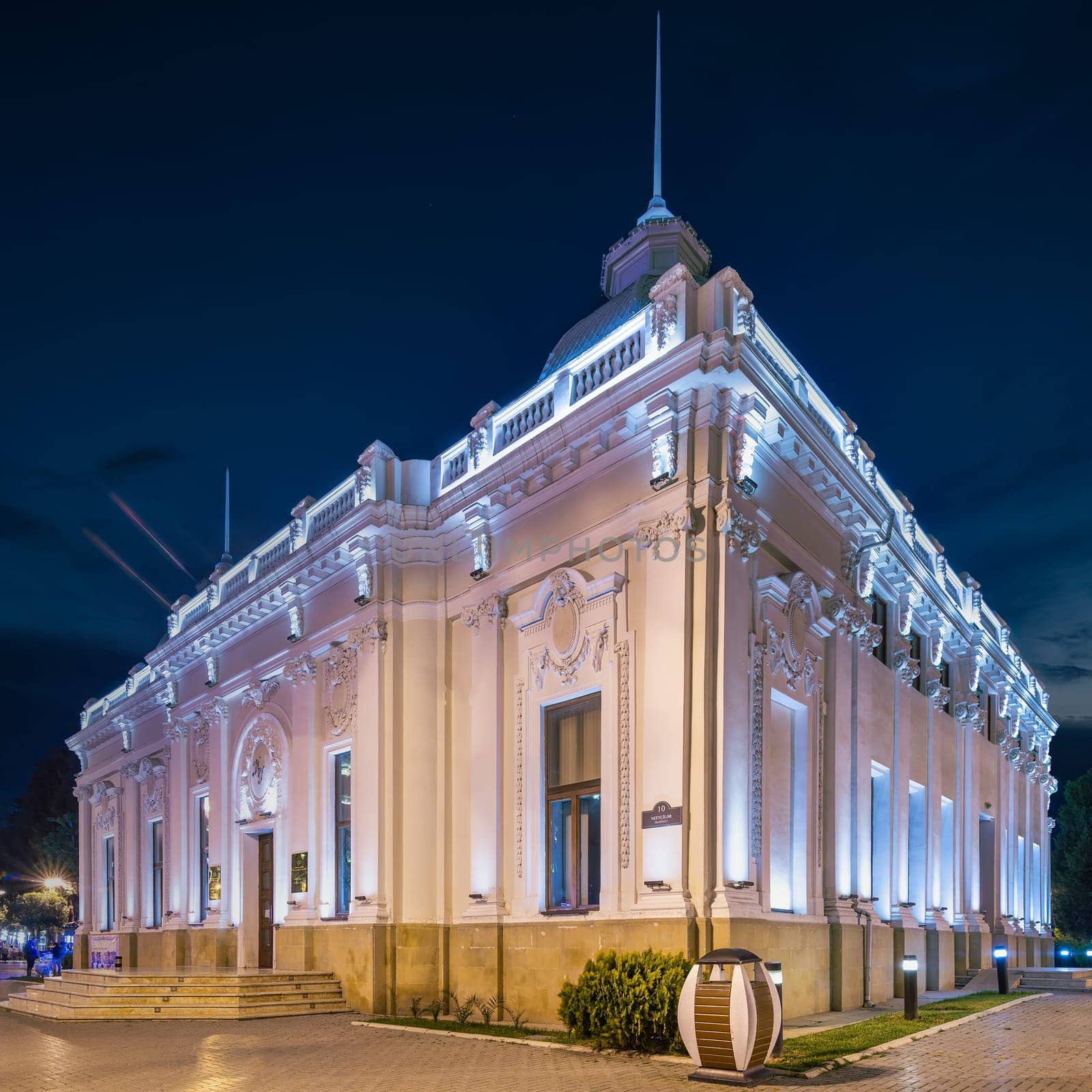 The Azerbaijan State Puppet Theatre in Baku stands brightly lit at night, highlighting its stunning architecture and serving as a cultural hub for performances and artistic expression