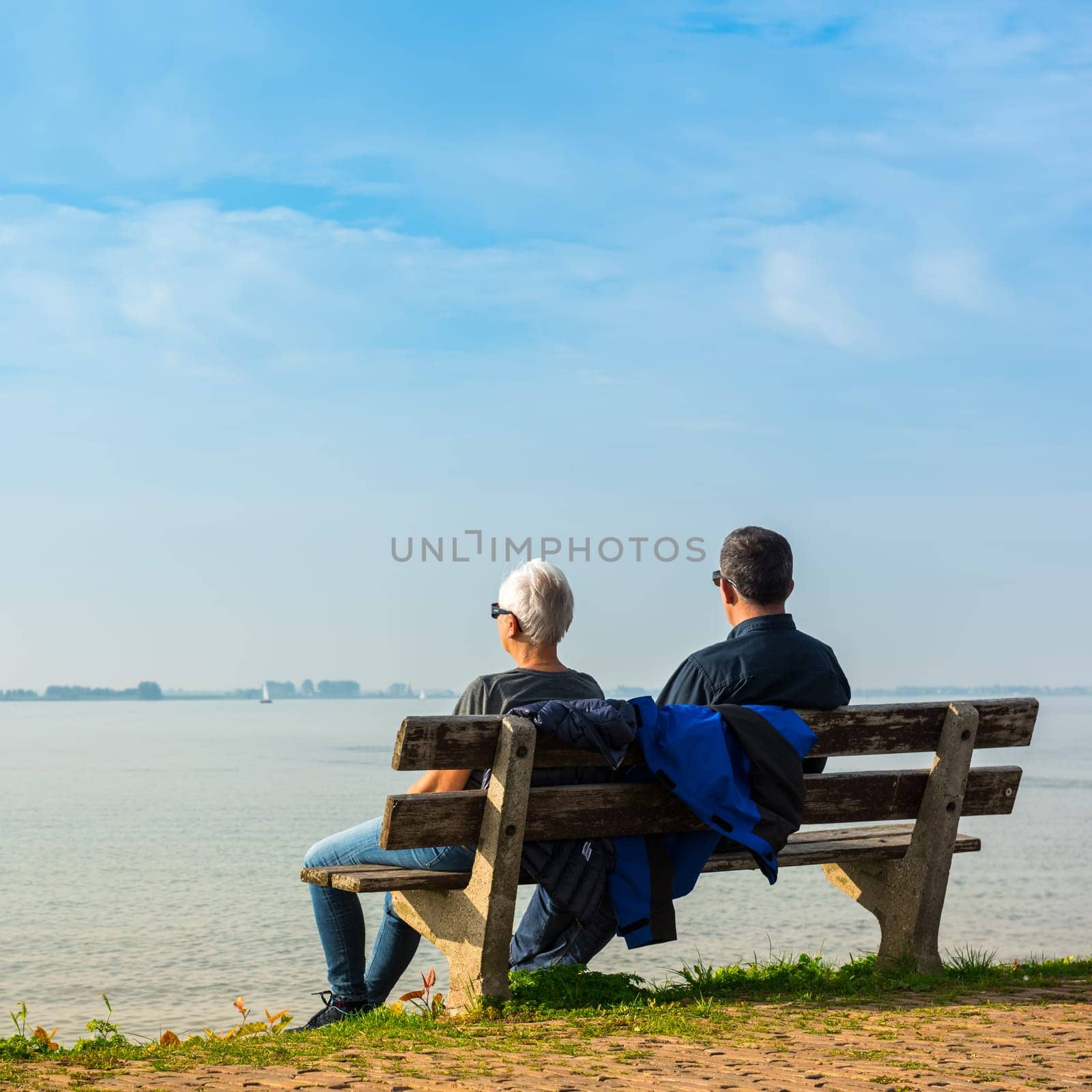 NETHERLANDS, MARKEN - OCTOBER 3: happy romantic middle aged couple enjoying sea view sitting on the bench on October 3, 2015