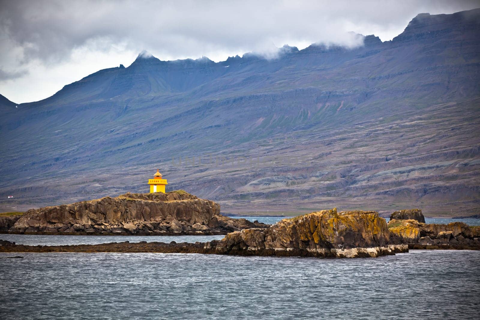 Iceland Sea and Mountains Landscape with Orange Lighthouse. Horizontal shot