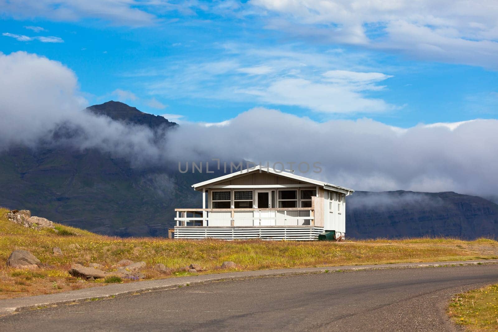 White Wooden House and asphalt road in East Iceland. Horizontal shot
