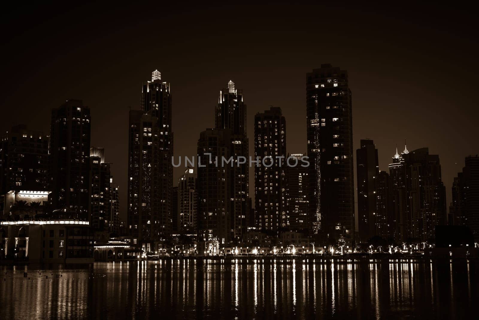 Night cityscape of Dubai city, United Arab Emirates. Reflections in the water. Sepia toned shot