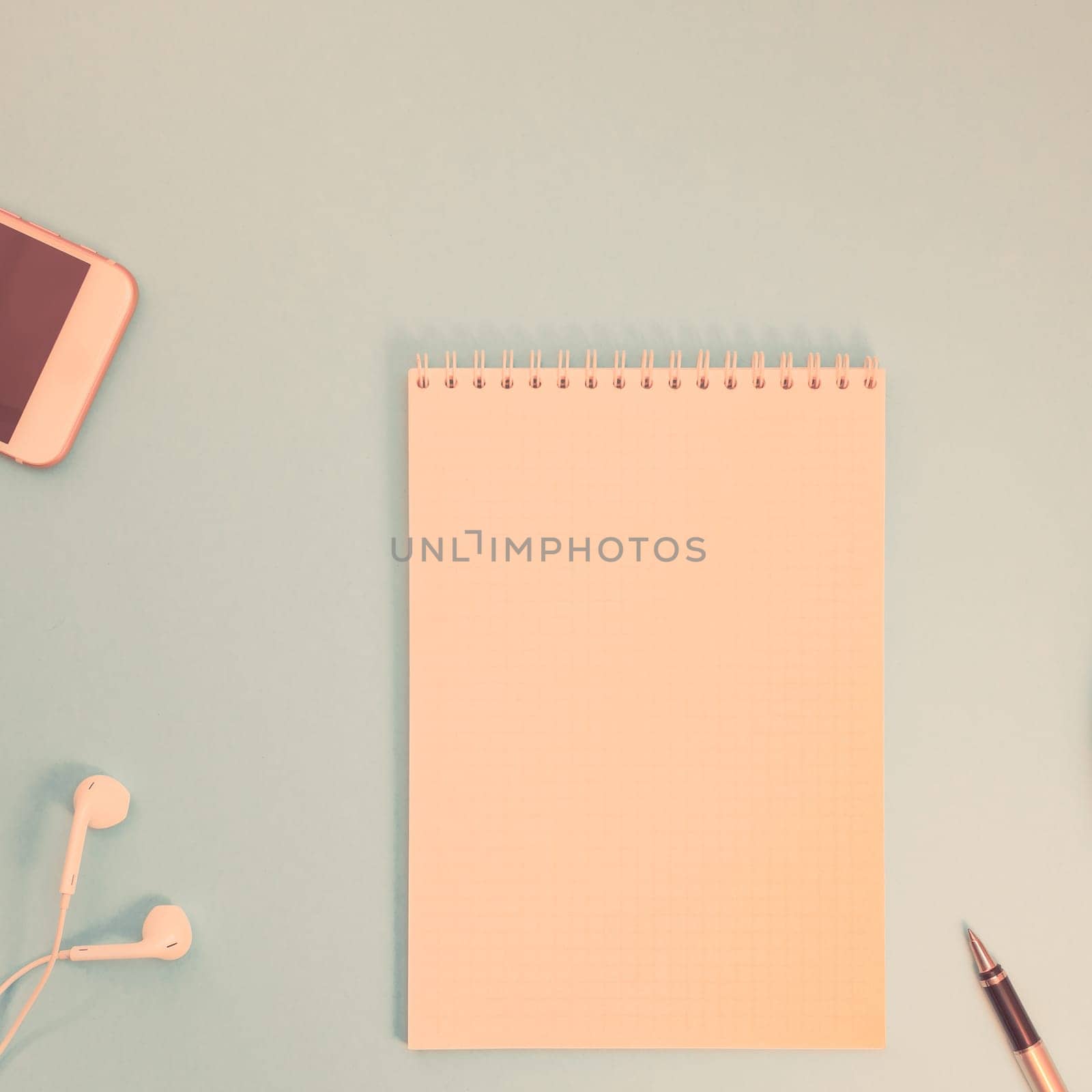 Creative flat lay photo of workspace desk with paper notebook, smartphone, earpieces, pen and coffee with copy space background minimal style