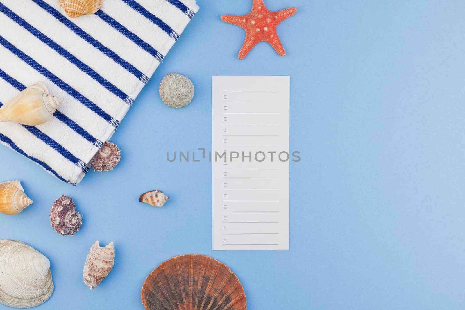 Creative flat lay concept of summer travel vacations. Top view of beach towel and seashells and starfish on pastel blue background with copy space in minimal style, template for text