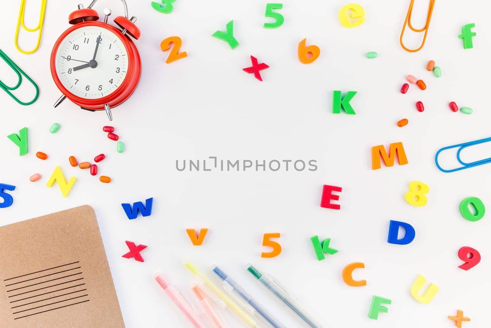Creative flat lay back to school concept with alarm clock, color school and office supplies on white table background with copy space, frame, template for text or design
