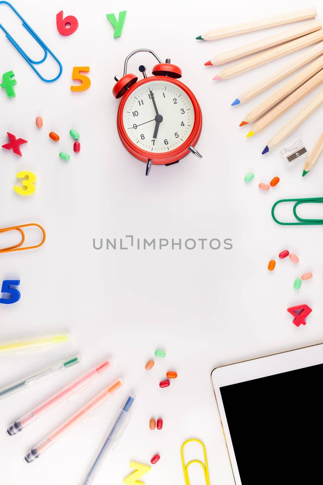 Creative flat lay back to school concept blank tablet with alarm clock, color school and office supplies on white table background with copy space, frame, template for text or design