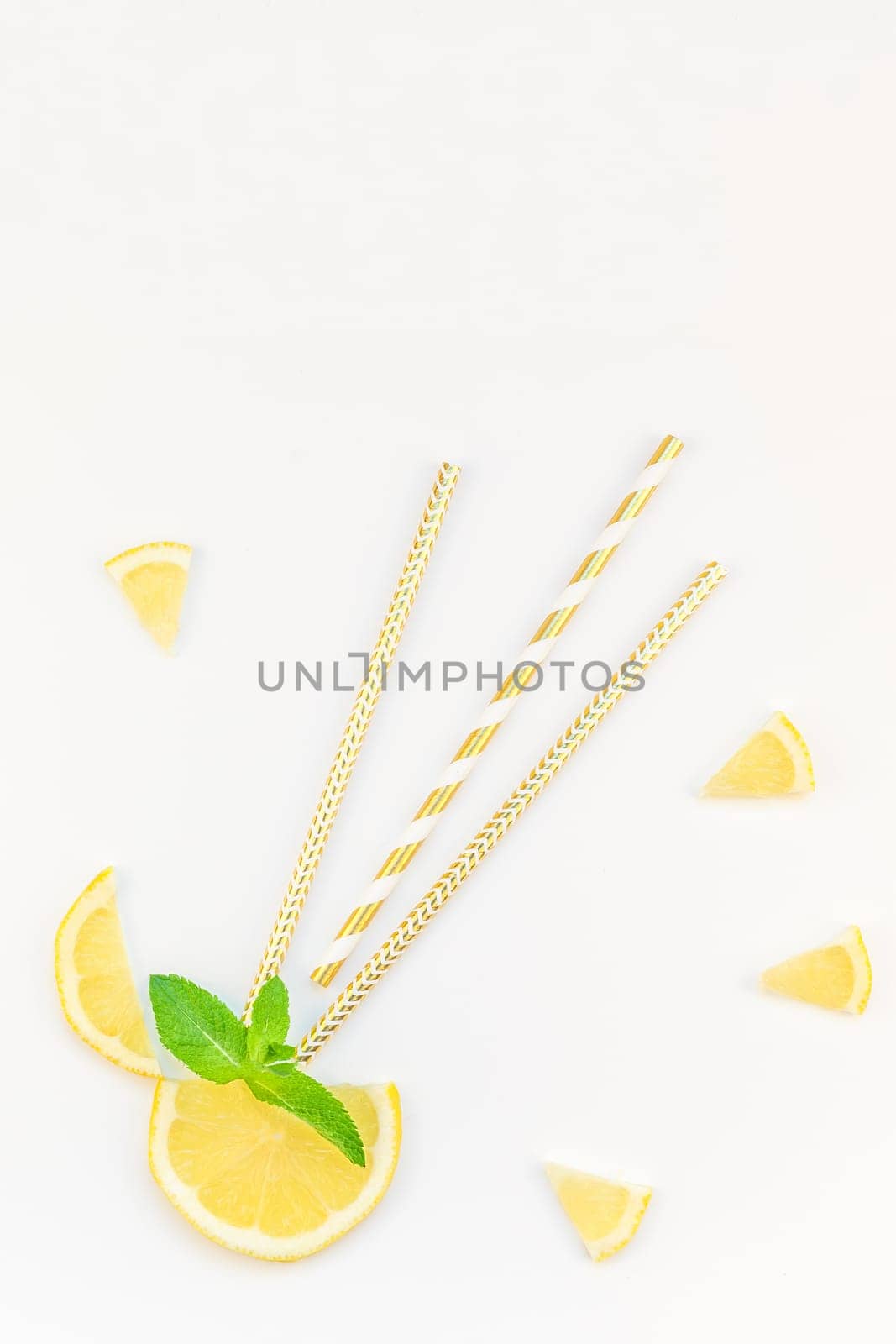 Creative flatlay overhead top view citrus lemon slices and mint herbs leaves white table background with copyspace. Hot summer refreshment lemonade concept. Beverage ingredients arranged with straws