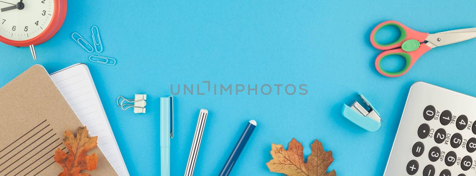 Creative flat lay top view back to school concept with color school and office supplies on bright turquoise paper table frame background with copy space, template for text or design. Long wide banner