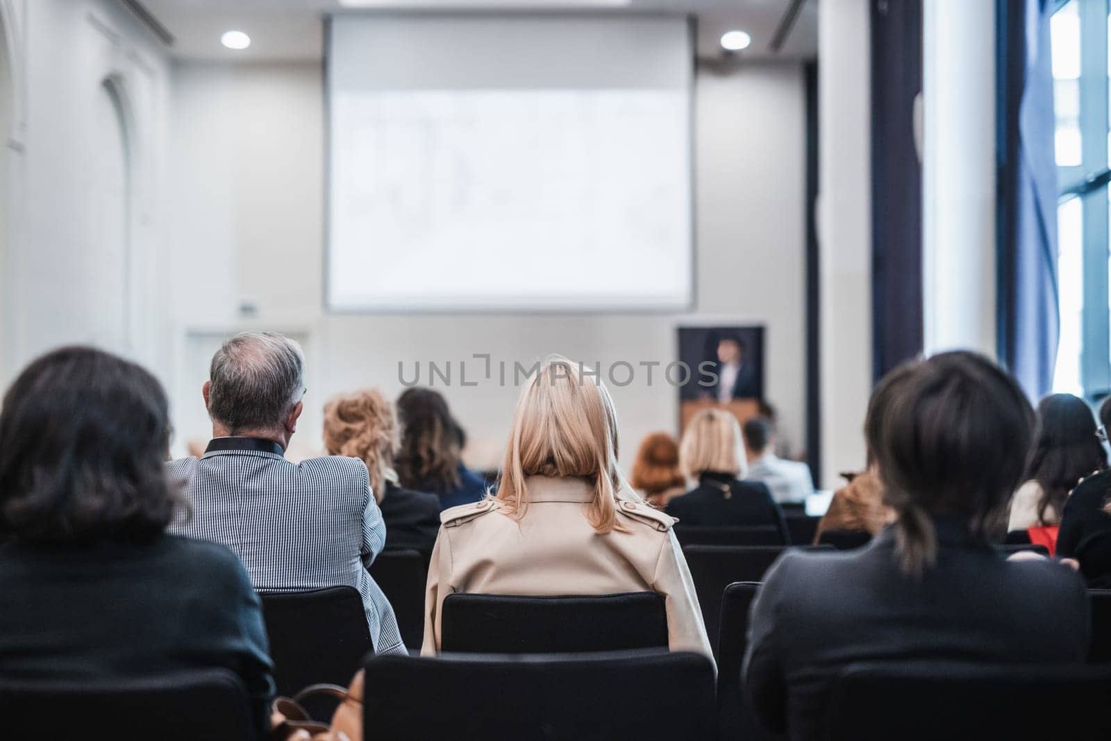 Speaker giving a talk in conference hall at business event. Rear view of unrecognizable people in audience at the conference hall. Business and entrepreneurship concept