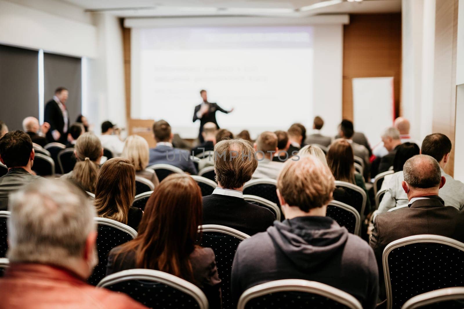 Speaker giving a talk in conference hall at business event. Rear view of unrecognizable people in audience at the conference hall. Business and entrepreneurship concept