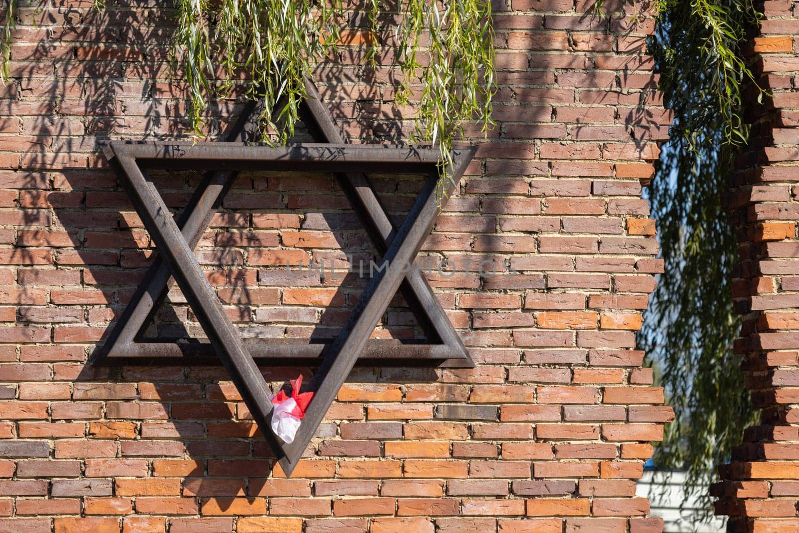Czestochowa, Poland - October 18, 2024: Monument to Jews of Czestochowa, commemorates 40,000 Jews murdered in the Treblinka death camp. Star of David made of railway rails, crack in red brick wall