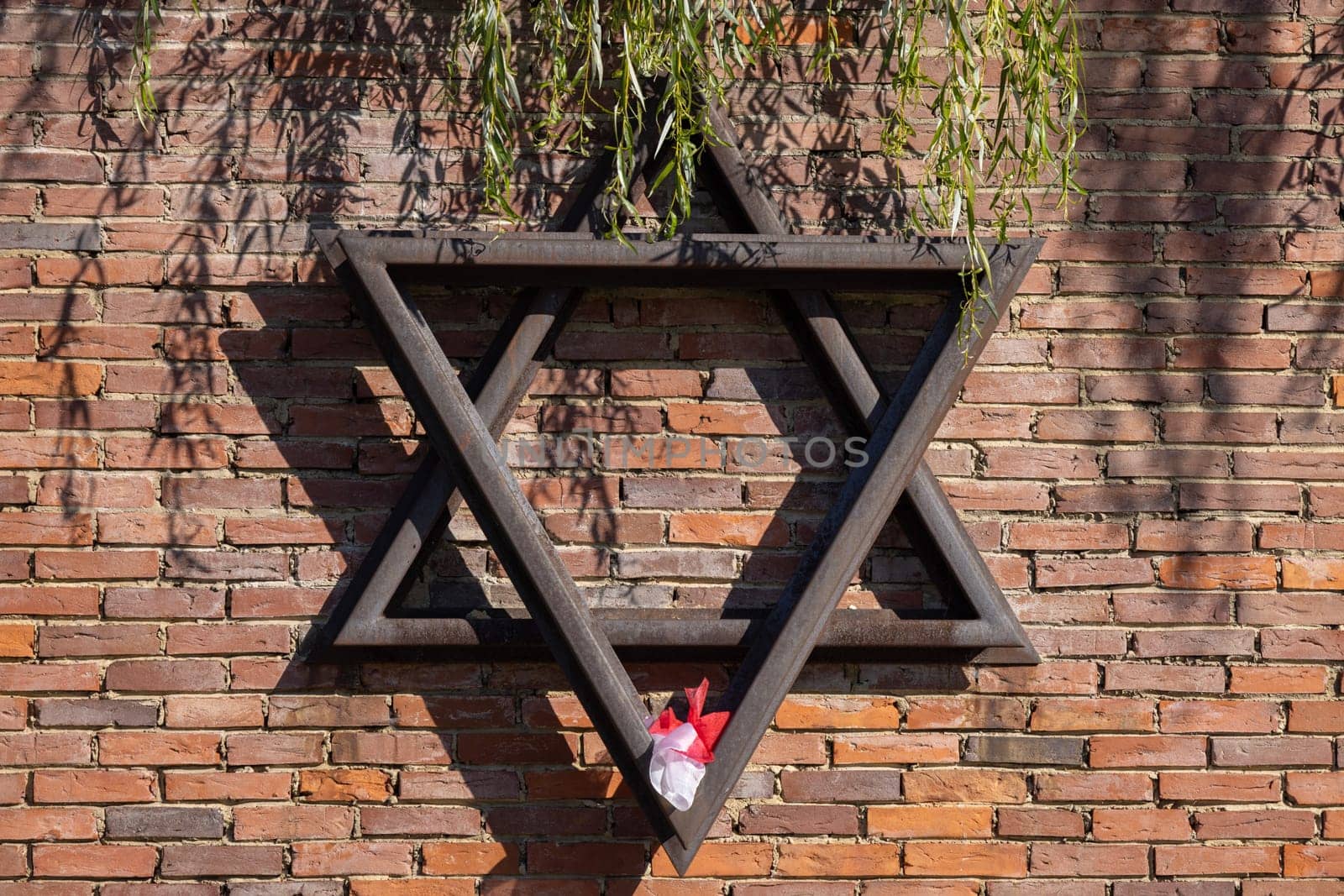 Czestochowa, Poland - October 18, 2024: Monument to Jews of Czestochowa, commemorates 40,000 Jews murdered in the Treblinka death camp. Star of David made of railway rails, crack in red brick wall