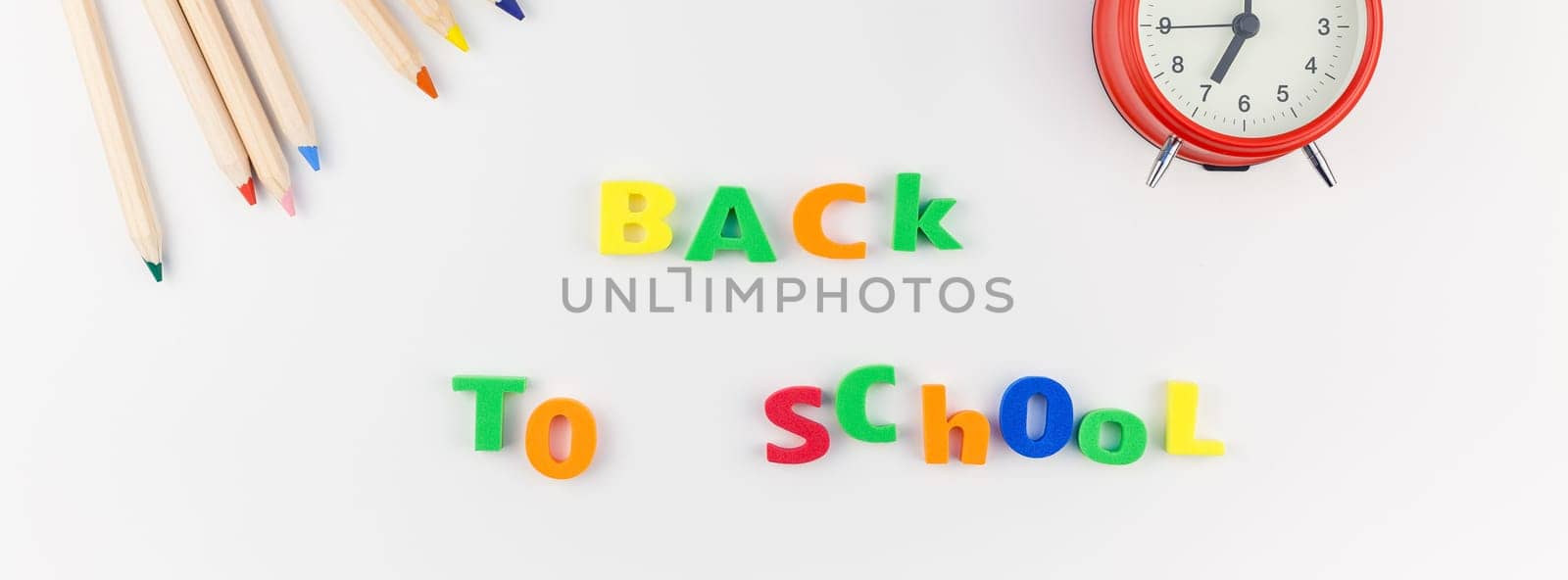Long wide banner back to school concept with alarm clock, color school and office supplies on white table background with copy space, frame, template for text or design