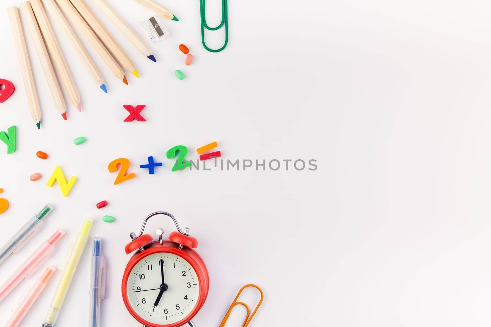 Creative flat lay back to school concept with alarm clock, color school and office supplies on white table background with copy space, frame, template for text or design
