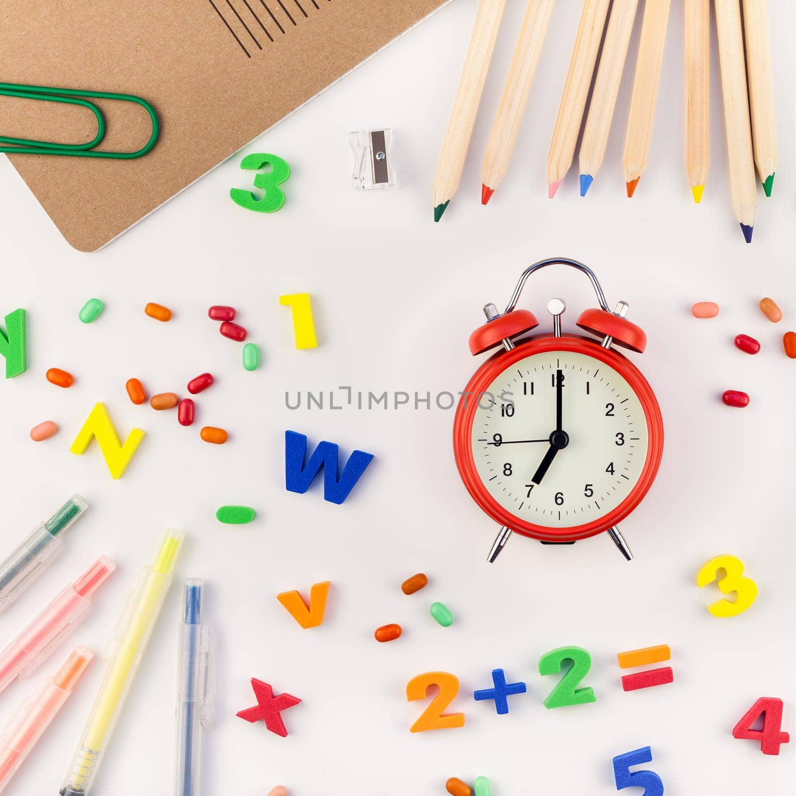 Square flat lay back to school concept with alarm clock, color school and office supplies on white table background with copy space, frame, template for text or design