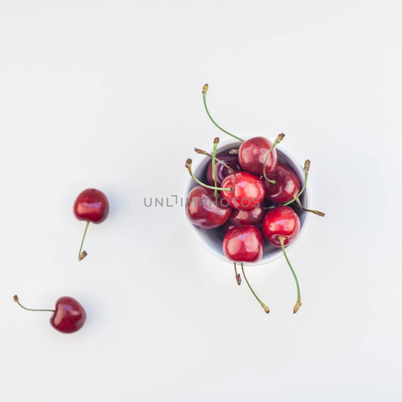 Square top view of fresh ripe cherry in a bowl with copy space isolated on white background in minimal style. Concept of summer fun and healthy eating. Template for your text or food design