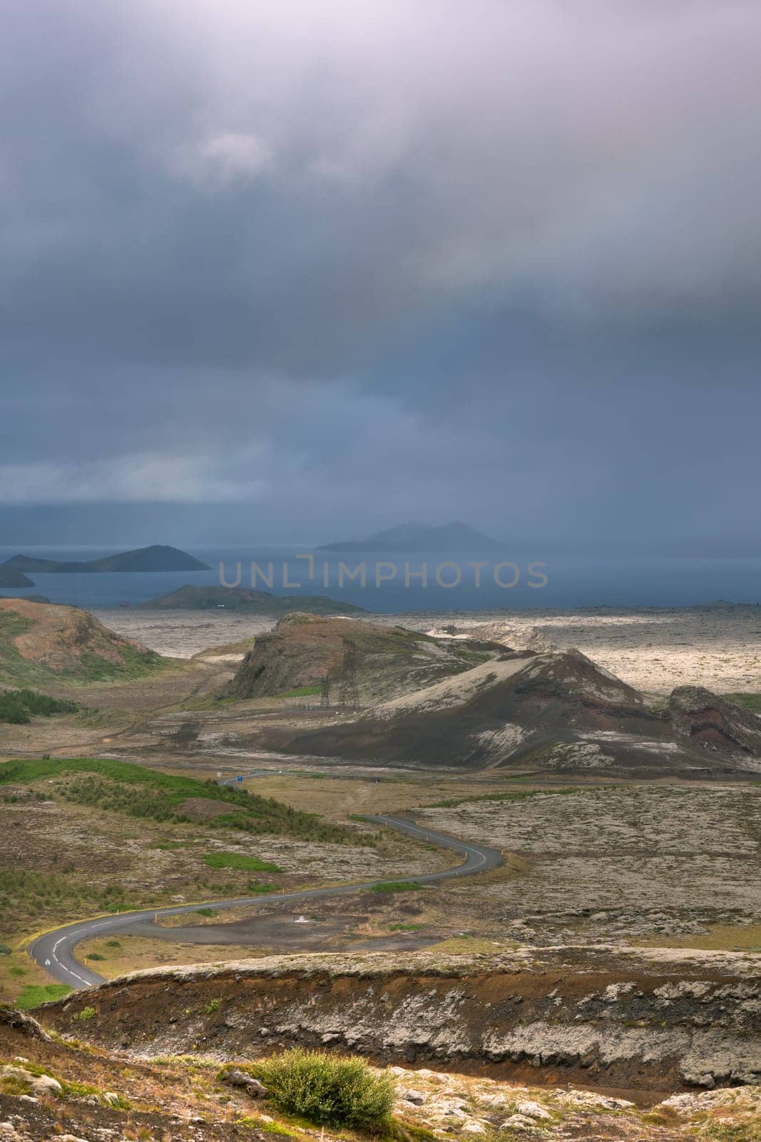 Highway through Iceland landscape at overcast day with rainbow. Vertical shot