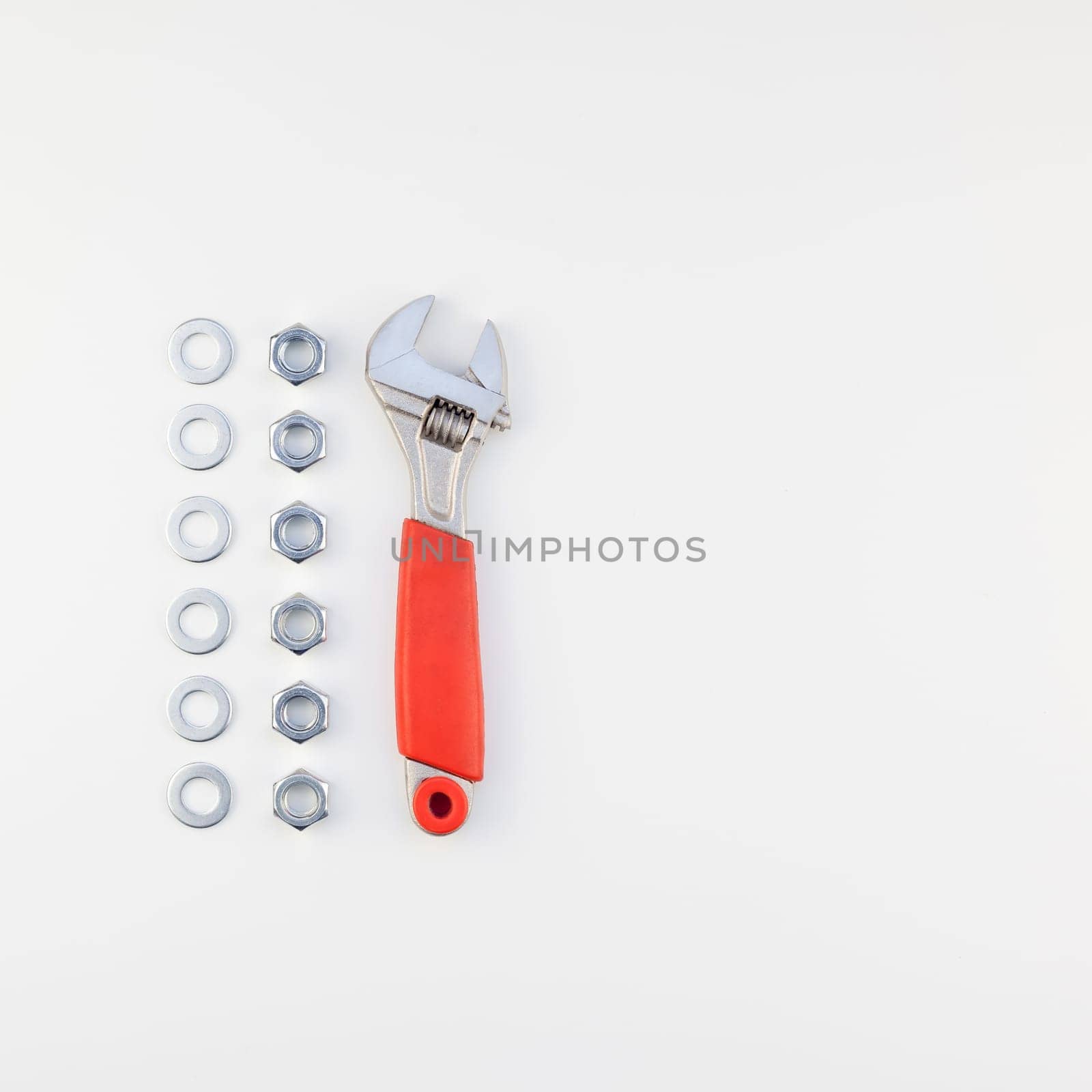 Creative square knolling Flat lay of metal nuts and spanner on white background with copy space. Repair or improvement top view concept.