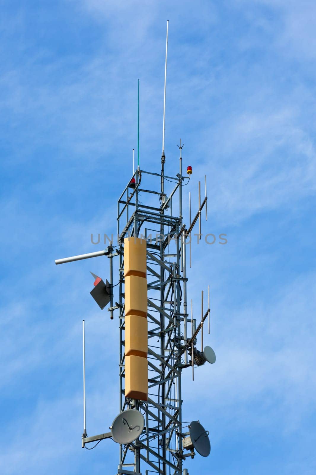 A radio communications tower with dishes against a blue sky