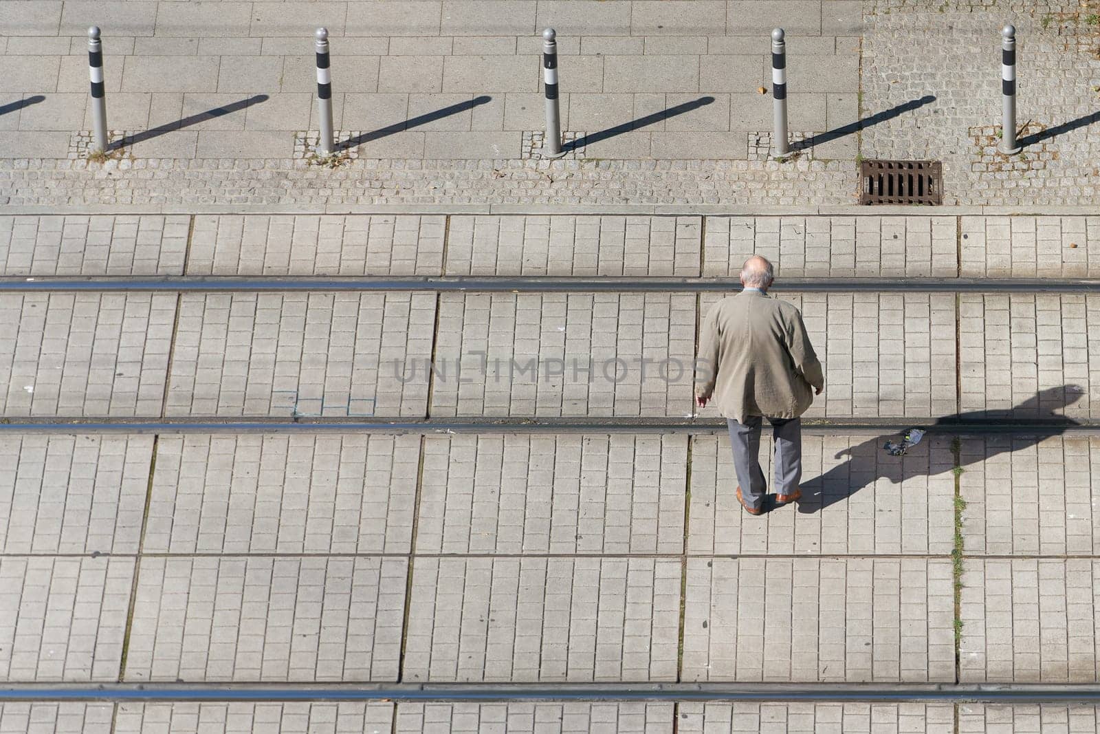 old pensioner in the city center crossing the tracks of a streetcar with text space on the left side