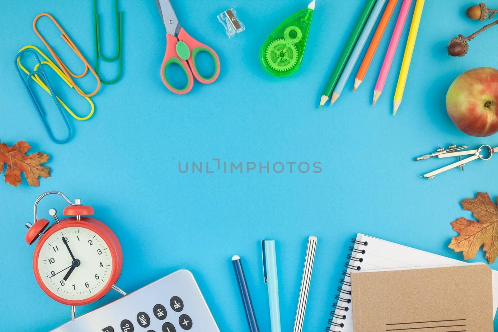 Creative flat lay top view back to school concept with alarm clock, color school and office supplies on bright turquoise paper table frame background with copy space, template for text or design