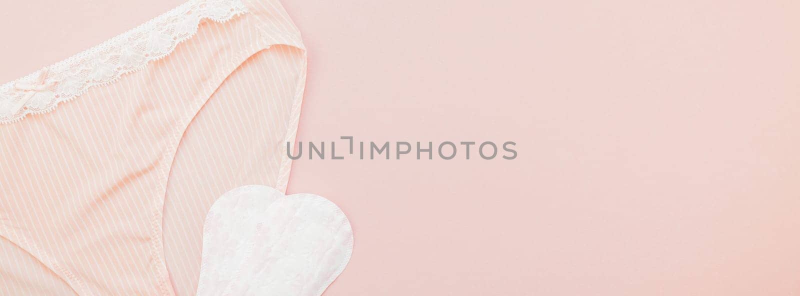 Feminine flat lay set of female panties and pads liners on pastel pink color long wide banner for fashion blog and social media with copy space for text