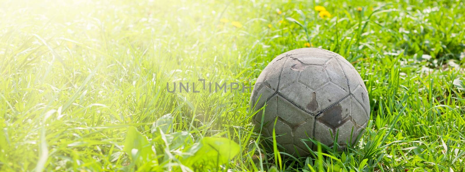 Old soccer ball forgotten in the green grass field. The football concept. Long wide banner