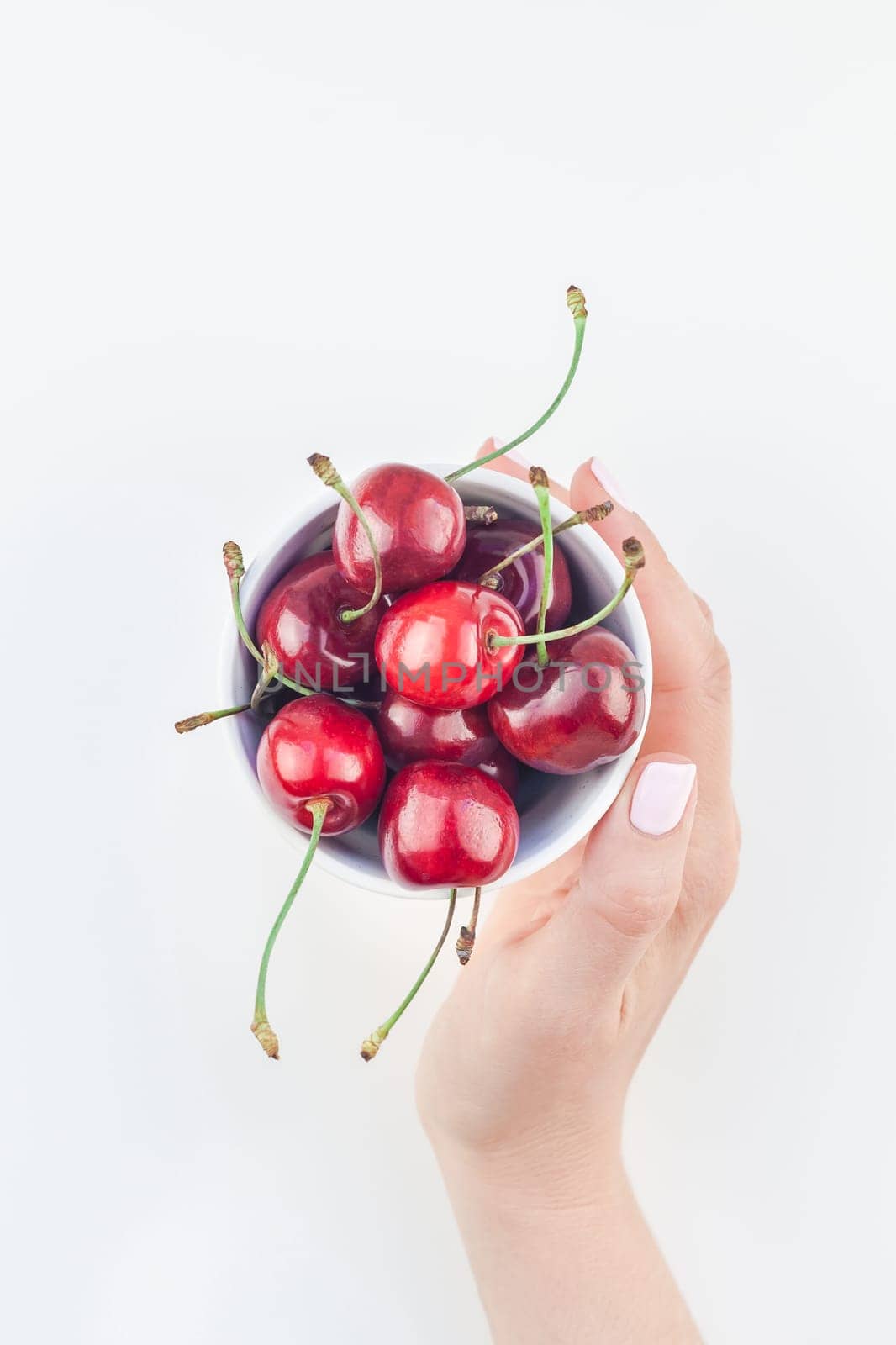 Creative top view of fresh ripe cherry in a bowl with hands and copy space isolated on white background minimal style. Concept of summer fun and healthy eating. Template for your text or food design