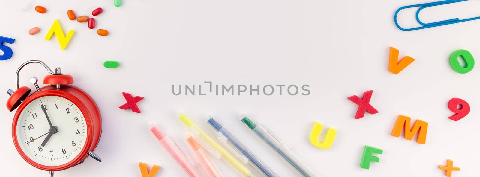 Long wide banner back to school concept with alarm clock, color school and office supplies on white table background with copy space, frame, template for text or design