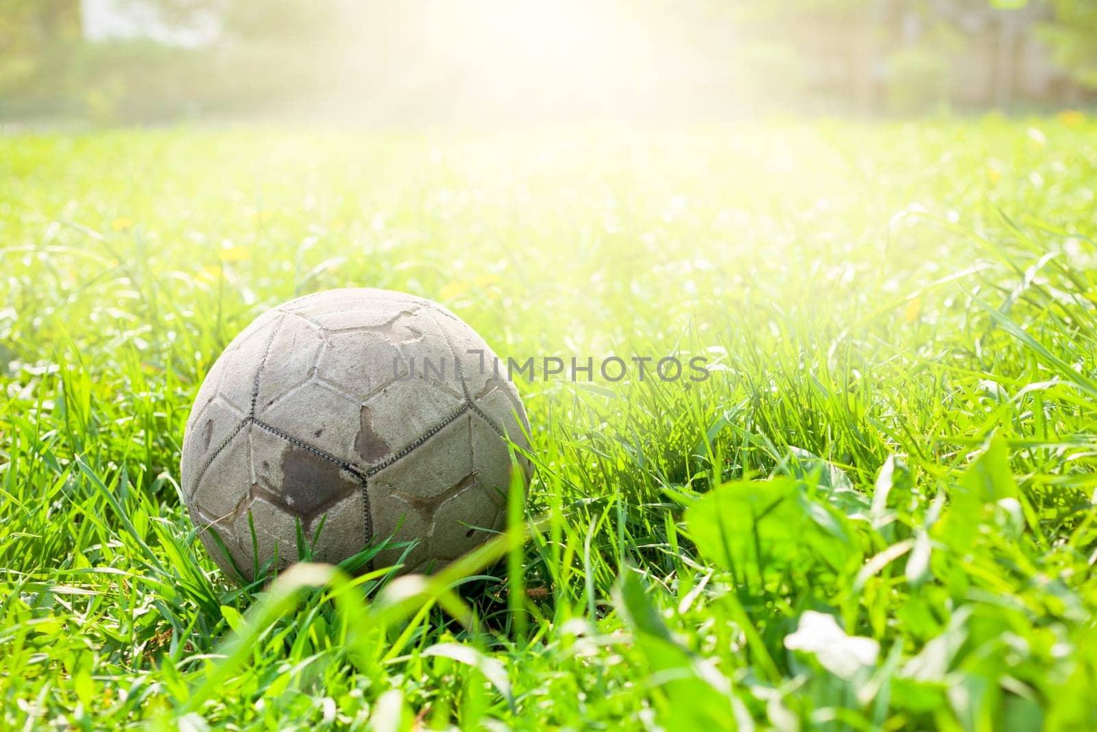 Old soccer ball forgotten in the green grass field. The football concept