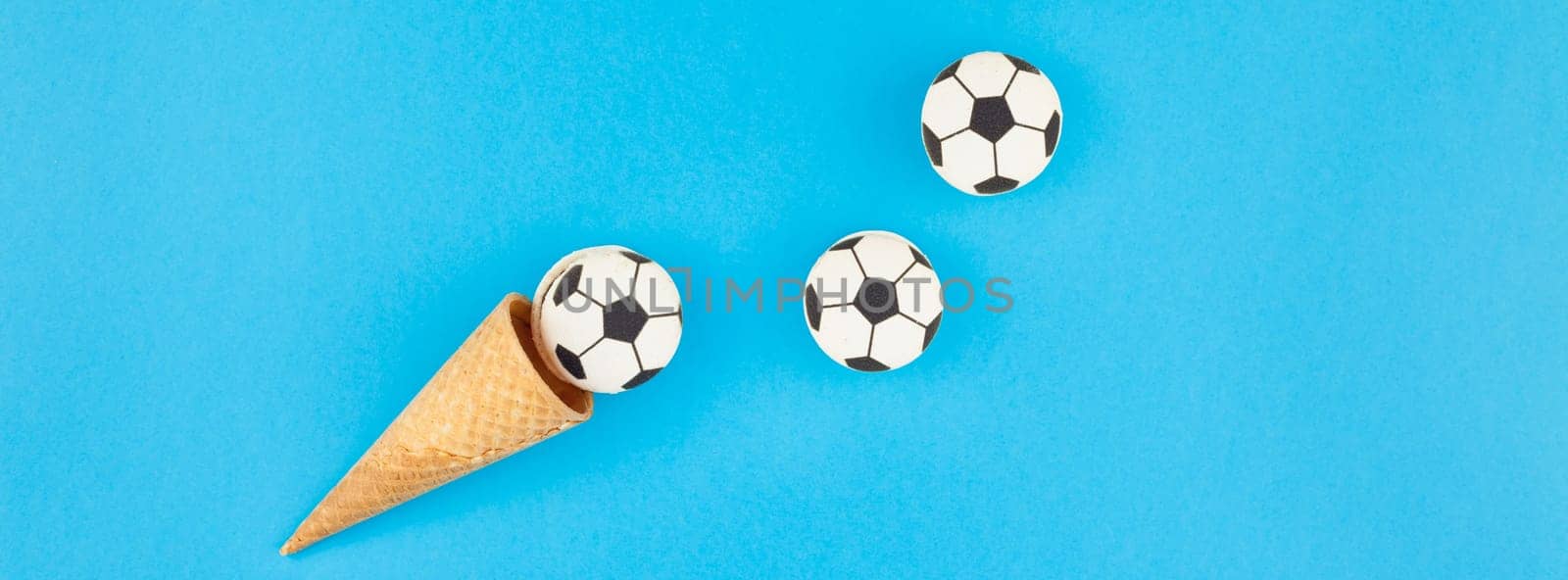 Long wide banner top view of ice cream waffle cones with soccer balls macarons on bright bold blue background with copy space in minimal style, concept of football games for children birthday